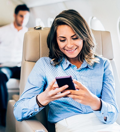 a woman sitting in an airplane looking at her phone
