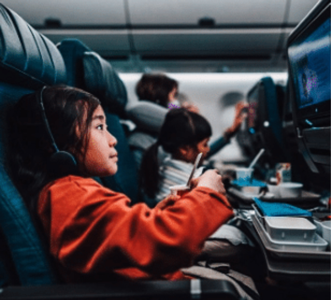 Child watching tv on airplane, representing inflight satellite connectivity.