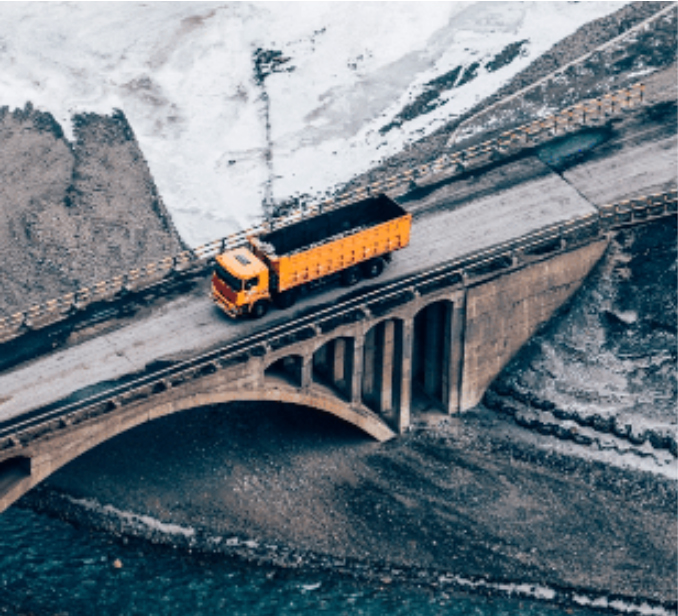 Yellow truck crossing a bridge, representing satellite connectivity for land-based transporation.