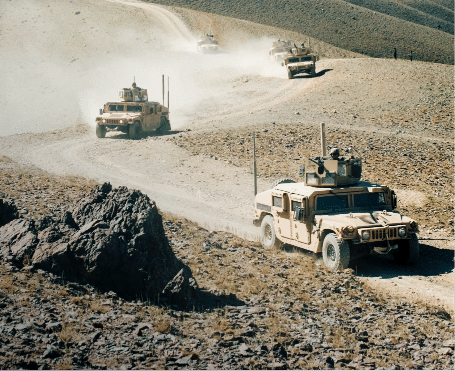 Military vehicles on a dirt road, highlighting the satellite solutions for governmental operations worldwide.